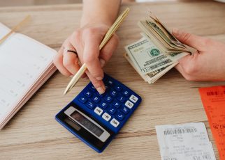 Hands handling cash and calculator for budget planning. Modern financial scene. — Factors That Affect Your Life Insurance Pre