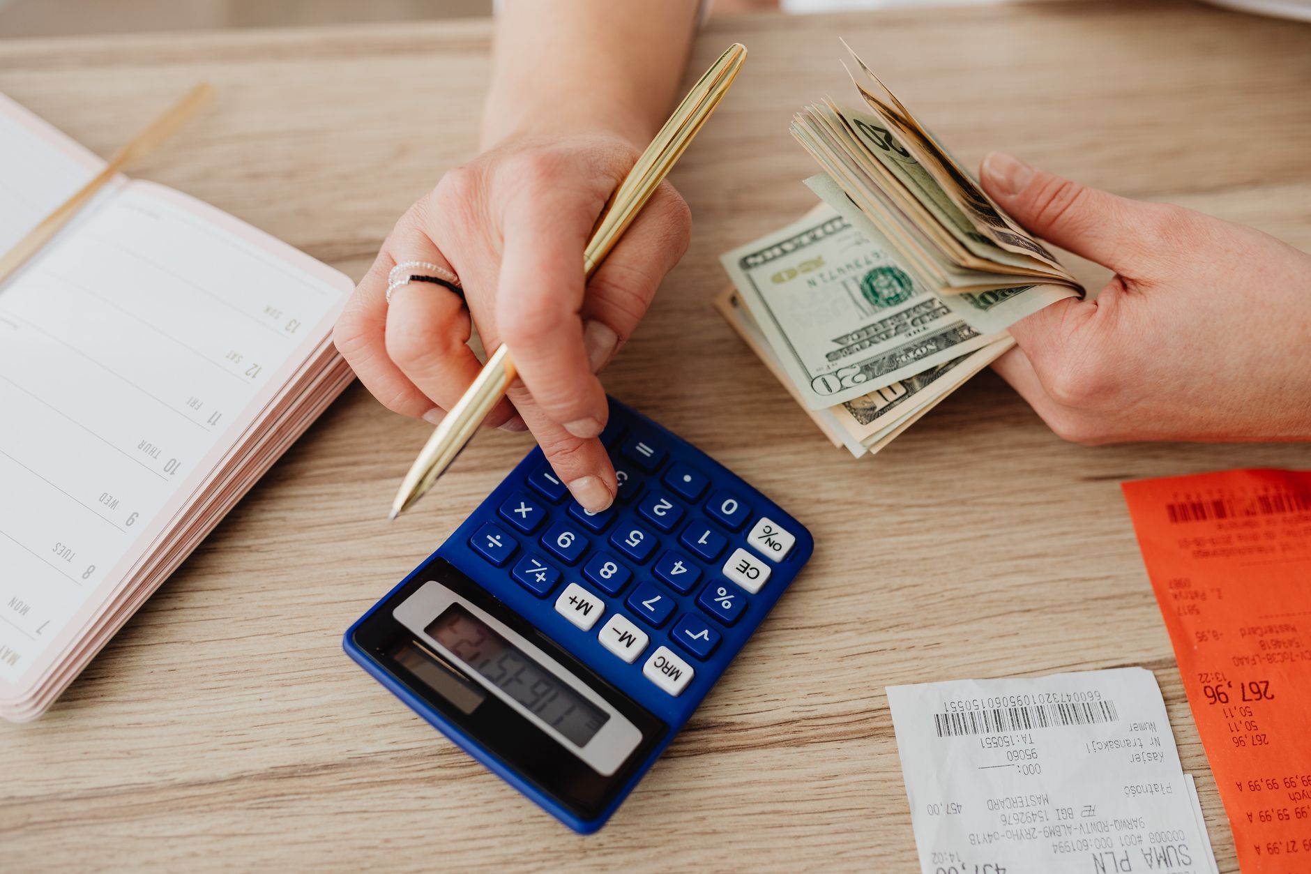 Hands handling cash and calculator for budget planning. Modern financial scene. — Factors That Affect Your Life Insurance Pre