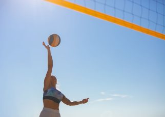 A woman spiking a volleyball on a sunny beach with a clear blue sky. — How to Stay Healthy and Energized on the Everest Base