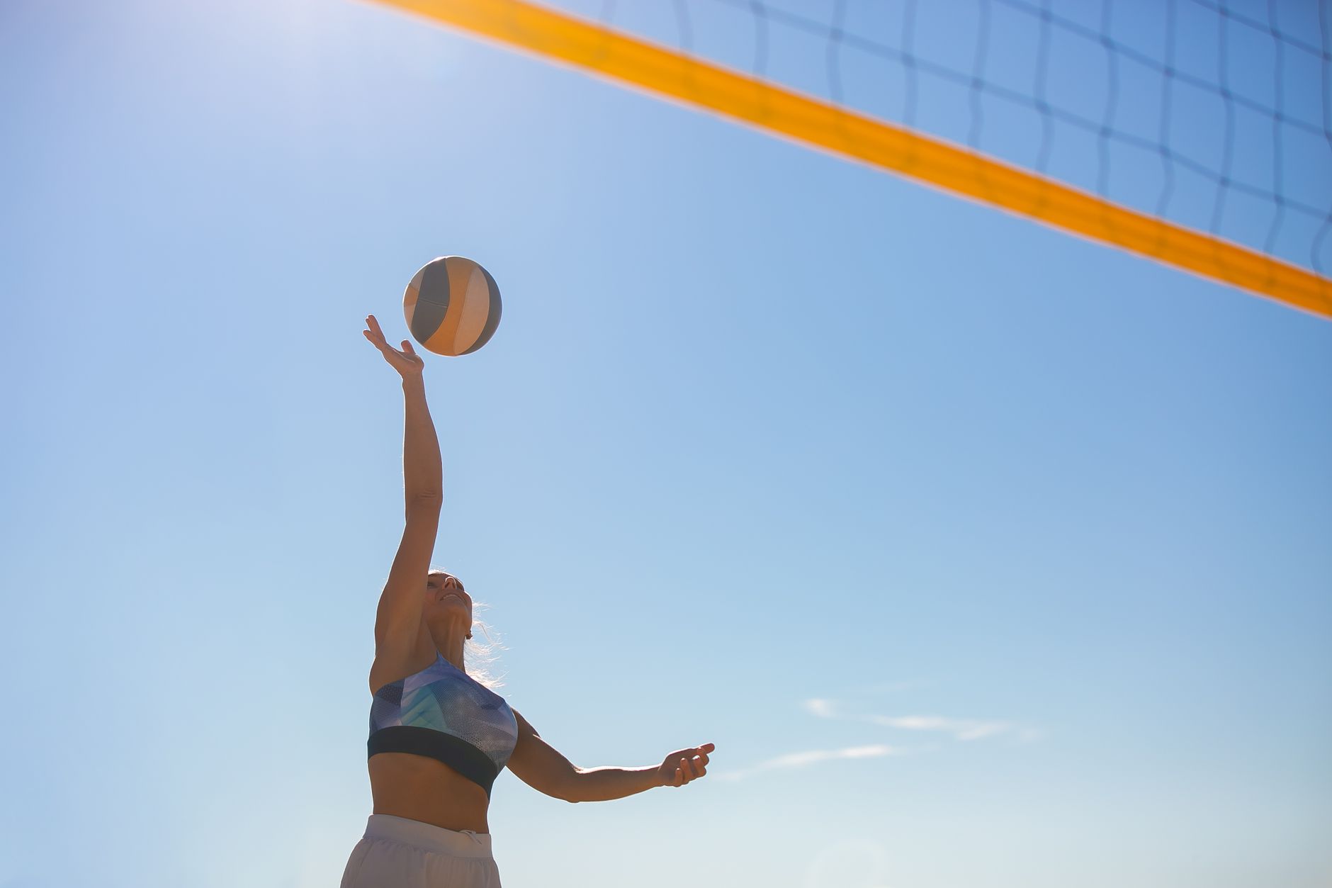 A woman spiking a volleyball on a sunny beach with a clear blue sky. — How to Stay Healthy and Energized on the Everest Base