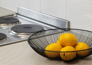 Lemons in a metal bowl on a kitchen counter beside an electric stove, highlighting freshness and simplicity. — Understanding